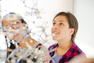 Curious girl students examining molecular structure in classroom