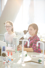 Obraz na płótnie Canvas Eager girl students behind microscopes in laboratory classroom