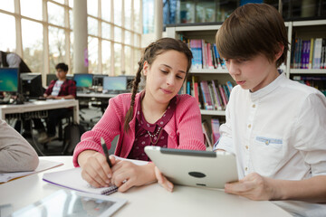 Students using digital tablet in library