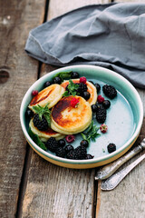 Sweet cottage cheese pancakes with raspberries, blackberries and currants in a plate close-up. Breakfast