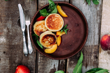 Sweet cheesecakes with peach in a plate close-up. Breakfast