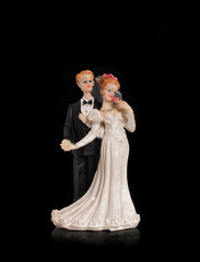 Bride and groom holding an old cake topper on a black background. Figurines for a wedding cake. - 455911693