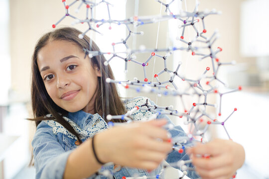 Portrait smiling girl student holding molecular model in laboratory classroom