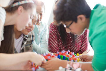 Female teacher and students examining DNA model in classroom