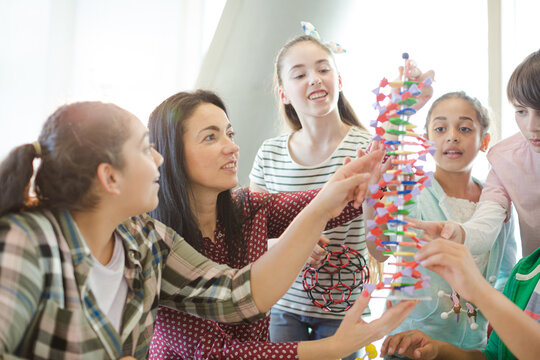 Female teacher and students examining DNA model in classroom