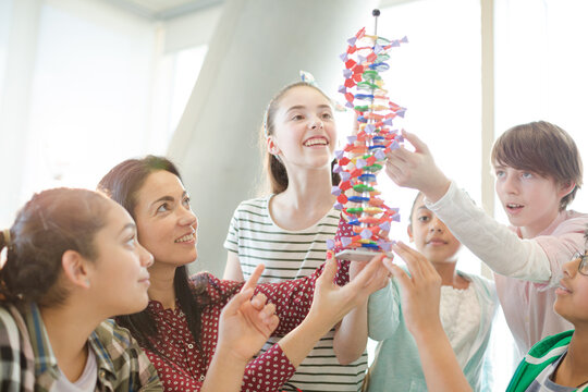 Female teacher and students examining DNA model in classroom