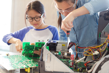 Girl students assembling computer in classroom