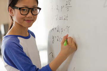 Girl student writing at whiteboard in classroom