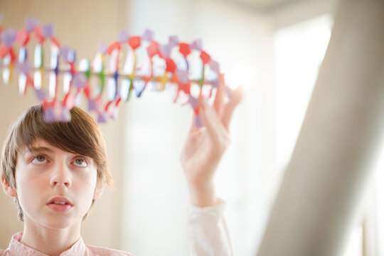 Boy student examining DNA model in classroom