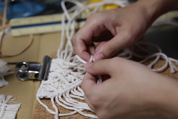 マクラメ編みでタペストリーを作成している手