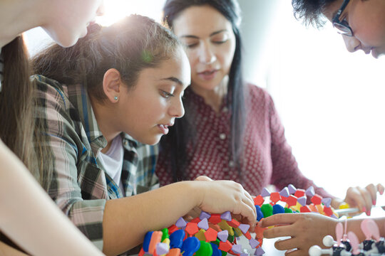 Female teacher and students examining DNA model in classroom