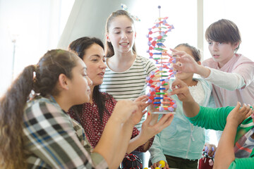 Female teacher and students examining DNA model in classroom