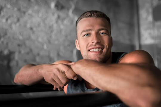 fitness, sport, training and lifestyle concept - smiling young man exercising on parallel bars in gym