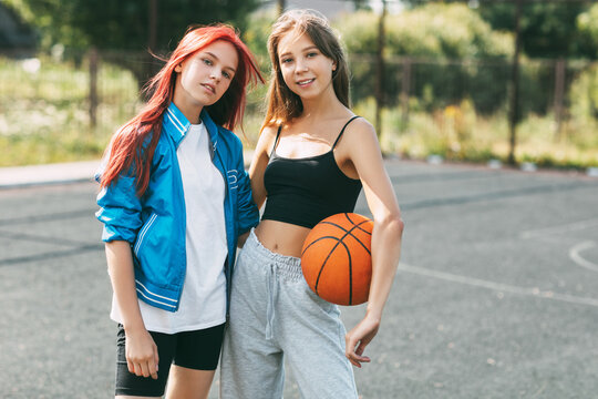 Portrait of two charming girls with a basketball on the sports field. Friendship, best friends, sports