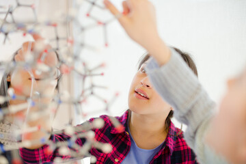 Curious girl students examining molecular structure in classroom