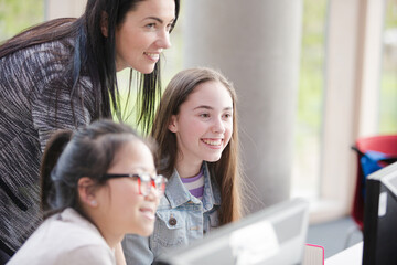 Female teacher and girl students using computer