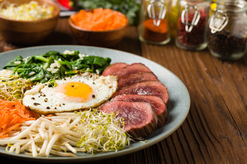 Obraz na płótnie Canvas Korean beef with sprouts, spinach and fried egg.