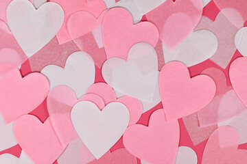 White and pink heart shaped paper confetti on pink background