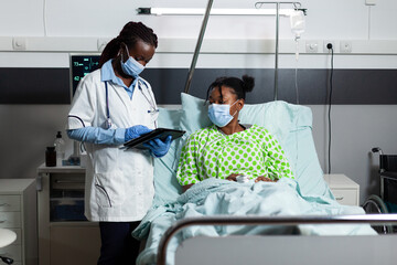 African american medic checking disease treatment on young patient with illness, sickness in...
