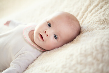 A charming baby in a white sunny bedroom. A newborn baby is resting in bed. Children's room for small children. Textiles and bed linen for children. Family morning at home. 