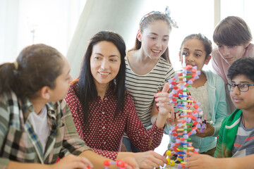 Female teacher and students examining DNA model in classroom