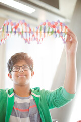 Boy student examining DNA model in classroom