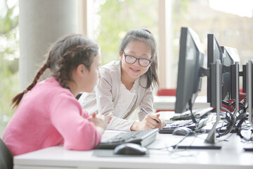 Fototapeta premium Girl students working at computer in library