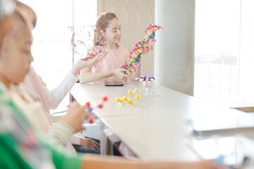 Confident students holding molecular structures in laboratory classroom