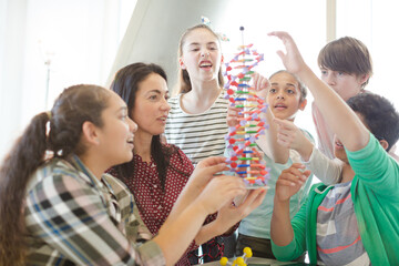 Female teacher and students examining DNA model in classroom