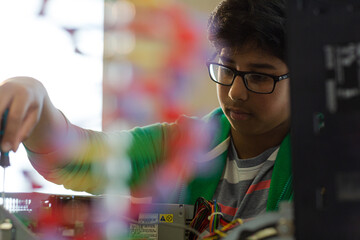 Focused boy student assembling computer in classroom