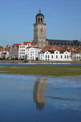 A view on the beautiful old buildings and the tower of the Great Church in the city of Deventer, The Netherlands, with its reflection in the ice