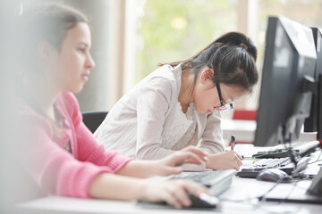 Girl students working at computer in library