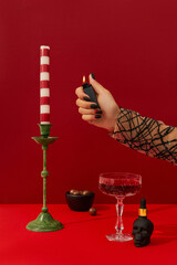 Womans hand with spooky nail design set the table. Halloween cocktail on red background