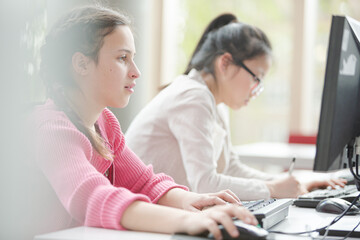 Fototapeta na wymiar Girl students working at computer in library