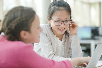 Girl students using laptop in library