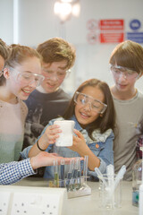 Curious, smiling students watching chemical reaction, conducting scientific experiment in laboratory classroom