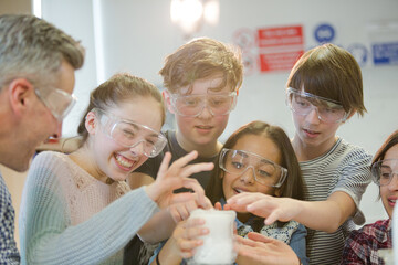 Curious, smiling students watching chemical reaction, conducting scientific experiment in laboratory classroom