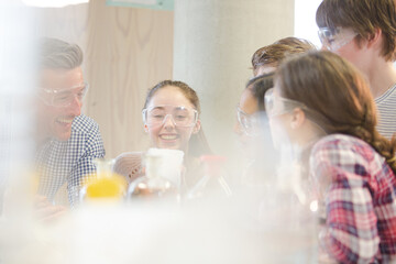 Male teacher and students watching chemical reaction, conducting scientific experiment in laboratory classroom