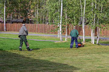 Men mow the grass in the lawn of an amusement park