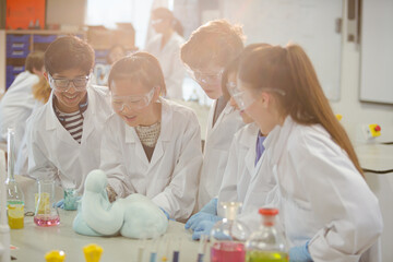 Surprised students conducting scientific experiment, watching chemical reaction in classroom laboratory