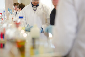 Boy students conducting scientific experiment, examining liquid in test tube in laboratory classroom
