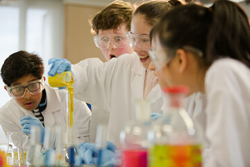 Surprised students conducting scientific experiment, watching chemical reaction in classroom laboratory