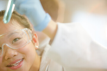 Girl students conducting scientific experiment, examining liquid in test tube in laboratory...