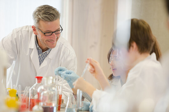 Male teacher and students conducting scientific experiment in laboratory classroom - Powered by Adobe