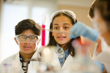 Students examining liquid in test tube, conducting scientific experiment in laboratory classroom