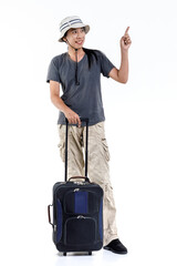 Isolated studio shot of Asian happy long hair ponytail male adventure traveler standing pointing on blank space for ads holding trolley traveling luggage for holiday vacation on white background