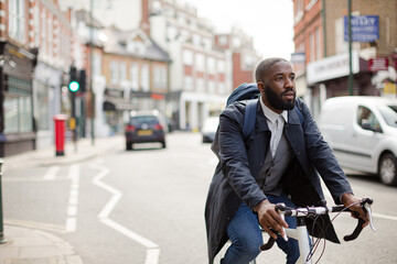 African businessman commuting, riding bicycle on urban street