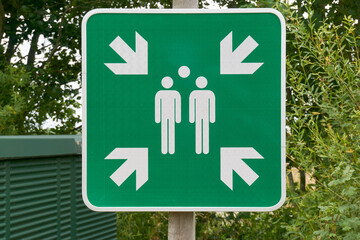 Evacuation assembly point sign in green and white. Gathering Point board to lead people to a safe place during an emergency.