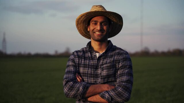 Mixed race male farmer standing in wheat fields smiling with arms crossed 