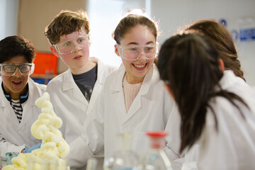 Surprised students conducting scientific experiment, watching chemical reaction in classroom laboratory